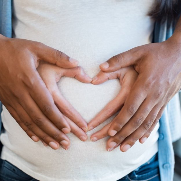 Picture of 2 hands forming a heart on a pregnant stomach