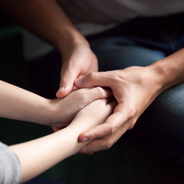 photo of man and woman holding hands in comforting manner