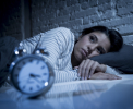 Image of tired woman looking at an alarm clock